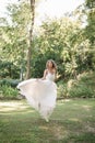 Young girl in a white dress in the meadow. Woman in a beautiful long dress posing in the garden. Stunning bride in a wedding dress Royalty Free Stock Photo