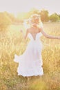 Young girl in a white dress in the meadow. Woman in a beautiful long dress posing in the garden. Stunning bride in a wedding dress Royalty Free Stock Photo