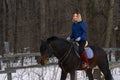 A young girl with white hair learns to ride a horse. The girl recently started to practice equestrianism. The girl is afraid of ri