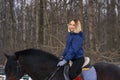 A young girl with white hair learns to ride a horse. The girl recently started to practice equestrianism. The girl is afraid of ri