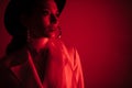 Young girl in a white suit and a black hat. The concept of clothing. Red light. Red background Royalty Free Stock Photo