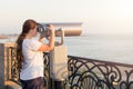 Young girl in white t-shirt looking through a coin operated binoculars on the sea shore. Woman look in touristic telescope on emba Royalty Free Stock Photo