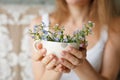 Young girl in a white tank holding a dotted cup with forget-me-not. Flowers in a mug. Hands with flowers. Royalty Free Stock Photo