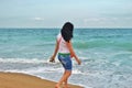 A young girl in a white Tshirt is walking along the sand in the sea. brunette on the shore of the azure sea in Bulgaria Royalty Free Stock Photo