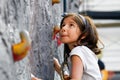Young Girl About to Climb Rock Wall Looks Up With a Bit of Worry