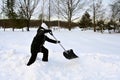 young girl in winter clothes cleans snow with big shovel in countryside. Teenage girl clears large snowdrifts Royalty Free Stock Photo