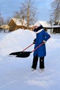 young girl in winter clothes cleans snow with shovel in countryside. Royalty Free Stock Photo