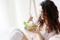 Young teenager wear pajamas eating fresh green diet salad Royalty Free Stock Photo