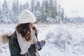 Young girl, woman with mobile phone walks in beautiful winter forest among trees, firs, covered with snow. Magnificent nature and Royalty Free Stock Photo