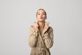 Portrait of young girl woman in a trench coat sends a kiss to the camera. Studio photo. Positive emotions, congratulations. Copy