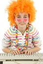 Young girl working on a computer and disguised with fun glasses and orange hair