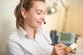 A young girl works in a call center. For a working place. Recording data. On the earphone with a microphone. Telecommunication.