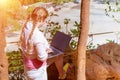 A young girl works with a laptop on the mountain overlooking the rainforest and the beach. Work and travel. Freelancer