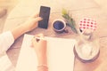 Young girl writes in a notebook with cell phone and cup of coffe Royalty Free Stock Photo