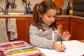 Young girl writes with pencil her homework in the kitchen Royalty Free Stock Photo