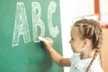 Young girl writing ABC on green chalkboard Royalty Free Stock Photo