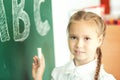 Young girl writing ABC on green chalkboard Royalty Free Stock Photo