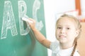 Young girl writing ABC on green chalkboard Royalty Free Stock Photo