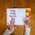 Young girl writing the words Today is my Favorite day in a vintage diary