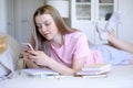 A young girl 15-18 years old lies on the bed with a phone in her hands. Royalty Free Stock Photo