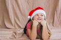 Little smiling girl in a red t-shirt with a santa claus hat lies on her stomach and smiles Royalty Free Stock Photo