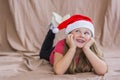 Little smiling girl in a red t-shirt with a santa claus hat lies on her stomach and smiles Royalty Free Stock Photo