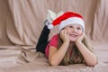 Little smiling girl in a red t-shirt with a santa claus hat lies on her stomach and smiles Royalty Free Stock Photo