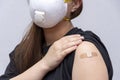 A young girl 18-20 years old in a medical mask points to a bandage with a vaccine against COVID-19, a coronavirus vaccination prog Royalty Free Stock Photo