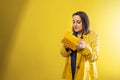 young girl on yellow background uncovering a box