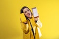 young girl on yellow background uncovering a box