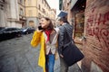 A young girl in a yellow raincoat bumped into a passerby while talking on the smartphone and walking the street on a rainy day.