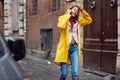 A young girl in a yellow raincoat is having a phone call while walking the city on a rainy day. Walk, rain, city Royalty Free Stock Photo