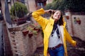 A young girl in a yellow raincoat in a street walk is in a good mood while enjoying music and rain in a cheerful manner. Walk, Royalty Free Stock Photo