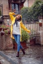 A young girl in a yellow raincoat in a street walk is in a good mood while enjoying music and rain. Walk, rain, city Royalty Free Stock Photo