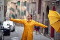 A young girl with a yellow raincoat and umbrella in a city walk is excited about rain drops falling on her. Walk, rain, city Royalty Free Stock Photo