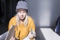 A young girl in a yellow sweater and two hats is horrified to study large bills, taxes and utility bills Royalty Free Stock Photo