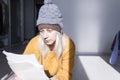 A young girl in a yellow sweater and two hats is horrified to study large bills, taxes and utility bills. Royalty Free Stock Photo