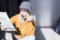 A young girl in a yellow sweater and two hats is horrified to study large bills, taxes and utility bills. Royalty Free Stock Photo