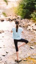 Young girl yoga meditating at sunrise sitting on stones on the shore of a mountain stream. Teenage model meditating in peaceful