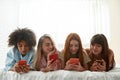 Young girlfriends chatting on smartphones on bed Royalty Free Stock Photo