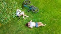 Young girls with bicycle in park, listening music with headphones and reading book, two student girls study and relax outdoors Royalty Free Stock Photo