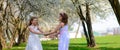 Young girls with blue eyes in white dresses in garden with apple trees blosoming Royalty Free Stock Photo