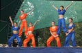 Young girls in bright suit dance and show acrobatic stunts on sc