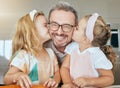 Young girls kiss father face, embracing them in their home. Portrait of daughters kissing the cheek of dad, having fun Royalty Free Stock Photo