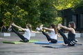 Young girls perform stretching for the legs. Group fitness lesson outdoors. Morning yoga in park