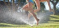 Young girls playing jumping in a garden water lawn sprinkler Royalty Free Stock Photo