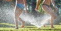 Young girls playing jumping in a garden water lawn sprinkler Royalty Free Stock Photo