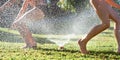 Young girls playing jumping in a garden water lawn sprinkler Royalty Free Stock Photo
