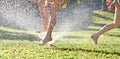 Young girls playing jumping in a garden water lawn sprinkler Royalty Free Stock Photo