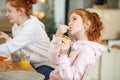 Young girls with red hair in the kitchen eating pizza, drinking juice. Get-togethers with girlfriends, two sisters Royalty Free Stock Photo